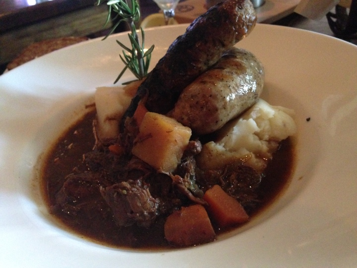 Bangers and Booz - a combination of bangers (sausages) on mashed potatoes surrounded by delicious beef stew